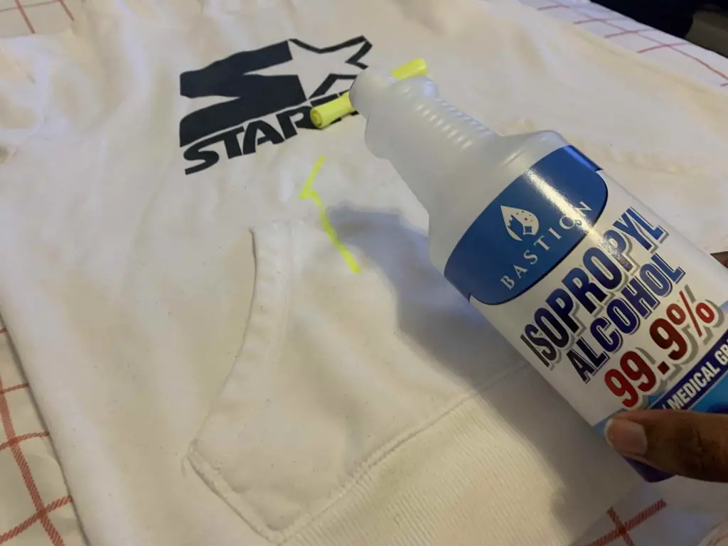 rubbing alcohol being poured onto a highlighter stain on a hoodie