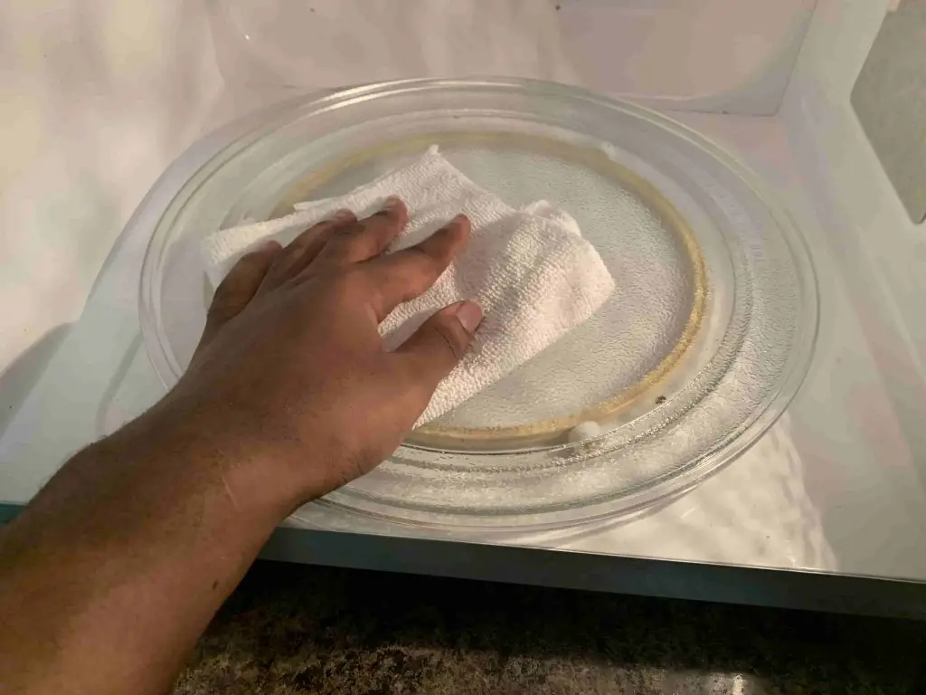 cleaning inside of a microwave with a vinegar soaked cloth