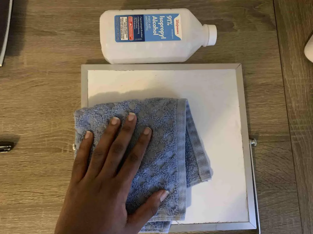 cleaning whiteboard using a cloth soaked with rubbing alcohol