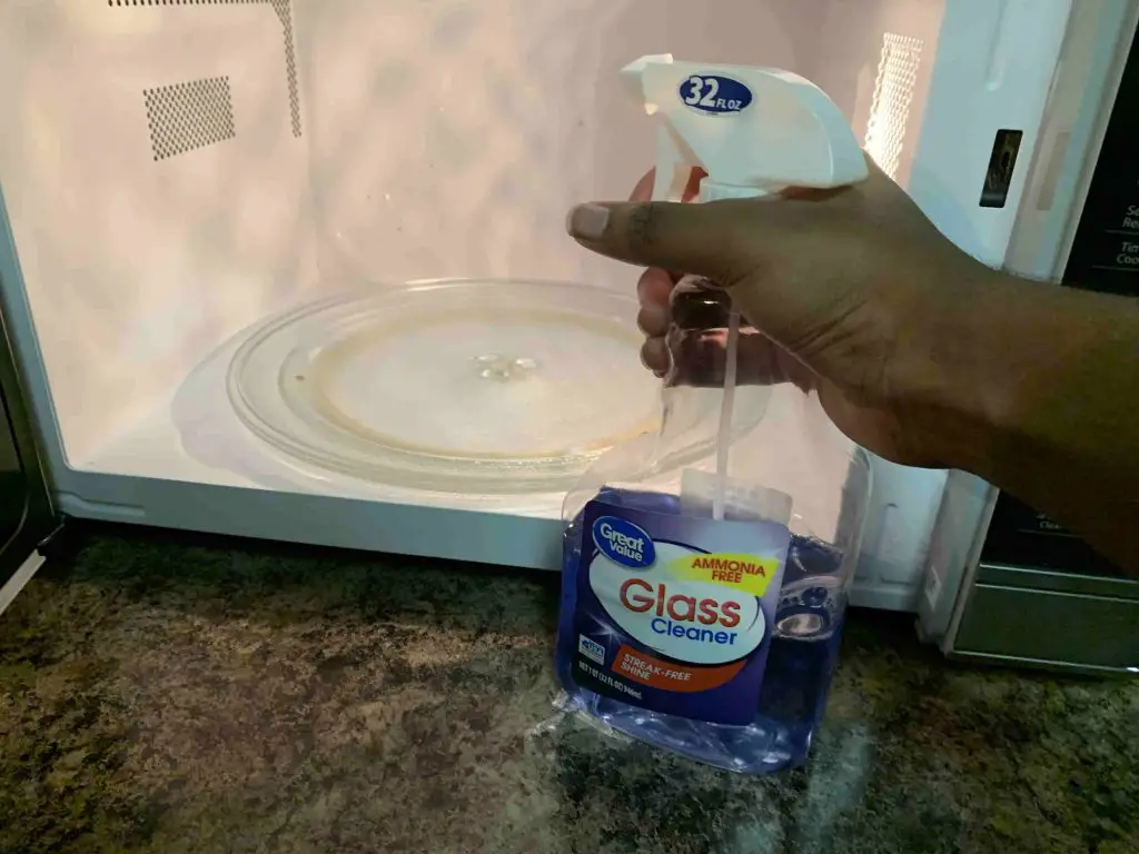 spraying glass cleaner inside of a microwave